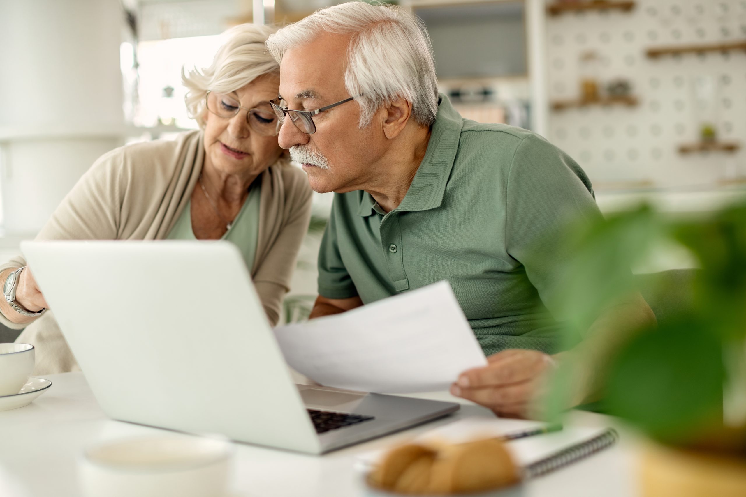 Couple de retraités examinant leurs documents financiers à la maison