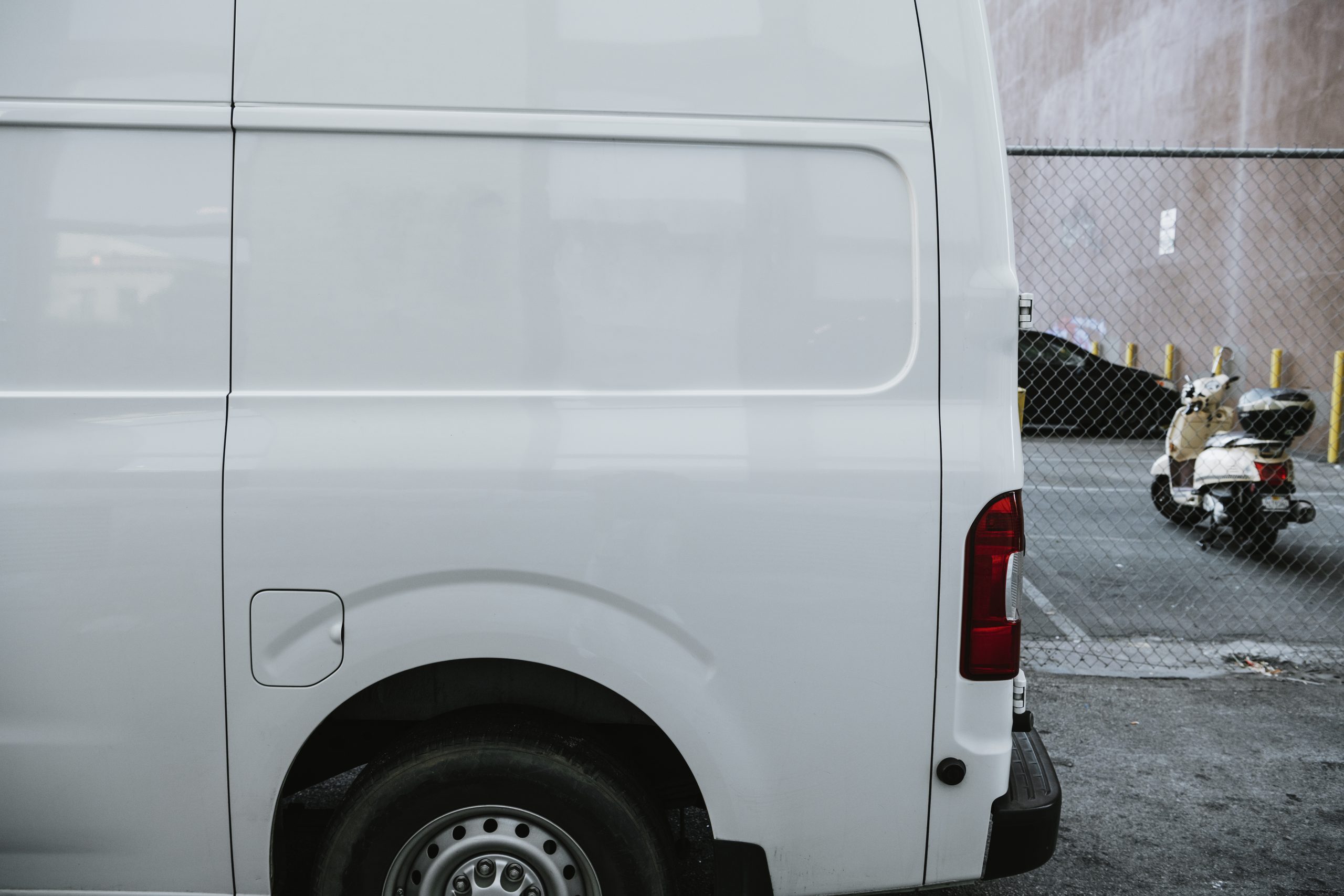 Fourgon utilitaire blanc stationne dans une rue etroite, portes arriere fermees