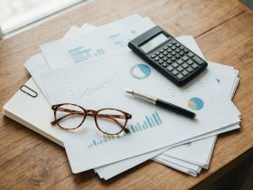Bureau vu de dessus avec tableaux financiers imprimés, calculatrice et stylo