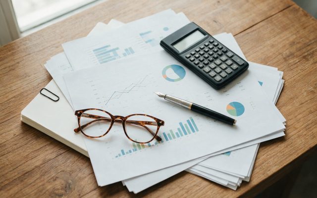 Bureau vu de dessus avec tableaux financiers imprimés, calculatrice et stylo
